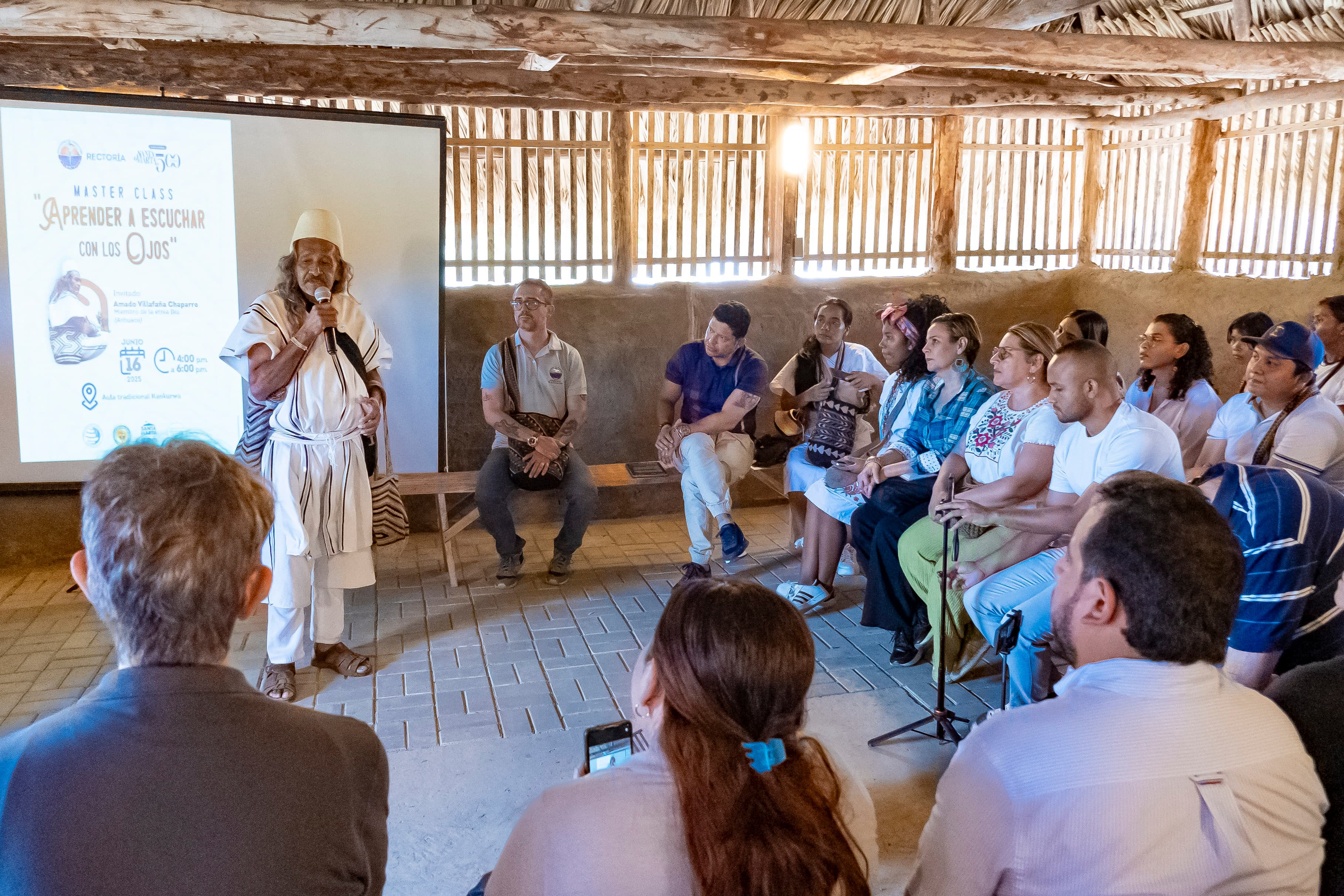 Un mayor del pueblo Ikʉ dirige la Master Class «Aprender a escuchar con los ojos» ante estudiantes y docentes, en el interior de la Kankʉrwa
